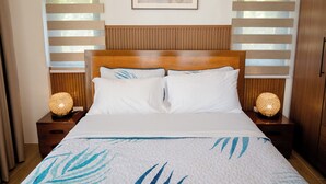 Habitación de hotel con una cama grande, cabecera de madera, dos mesitas de noche con lámparas y aire acondicionado instalado en la pared.