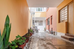 A narrow courtyard with potted plants, a bicycle, and a staircase leading to an upper level. - Cozy 2BR - Heart of Barranco - Walk to Everywhere (Lima)