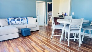 A living room with a sofa, ottoman, and a coffee table. - Modern Lake Front 4 Bedroom House with Private Dock (Roach)