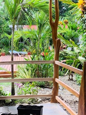 A wooden deck with a view of a lush garden. - Mecca- Casita de Reina (Cahuita)
