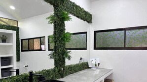 Un baño moderno con un espejo grande, un lavabo negro y un jardín vertical verde.