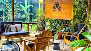 A wooden deck with a sofa, chairs, and a hanging sign with a logo.