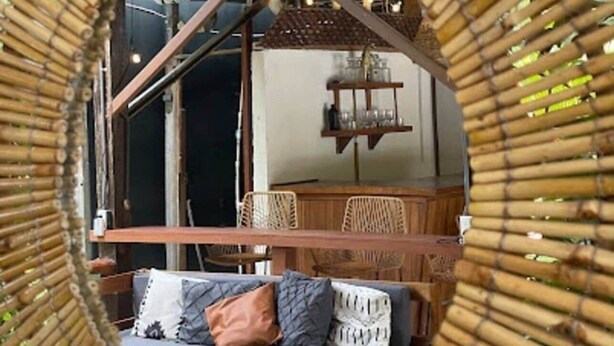 A circular view of a room with a hanging chair, a wooden table, and a wall-mounted shelf.