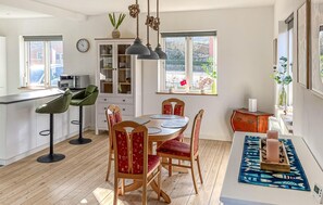 Een moderne keuken met een eethoek, houten vloeren en grote ramen.