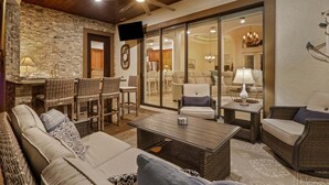 Un salon chaleureux avec des meubles en osier, un mur en pierre et un ventilateur de plafond.