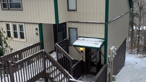 Un edificio de dos pisos con una escalera de madera que conduce a un porche cubierto.