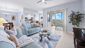 A spacious living room with a sofa, coffee table, and a balcony with a view. - Bonita Greens Retreat | Golf View Condo | Highland Woods | Near Bonita Beach (Bonita Springs)