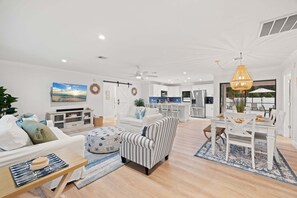 Ein modernes Wohnzimmer mit Sofa, Sessel, Esstisch und Küchenzeile.