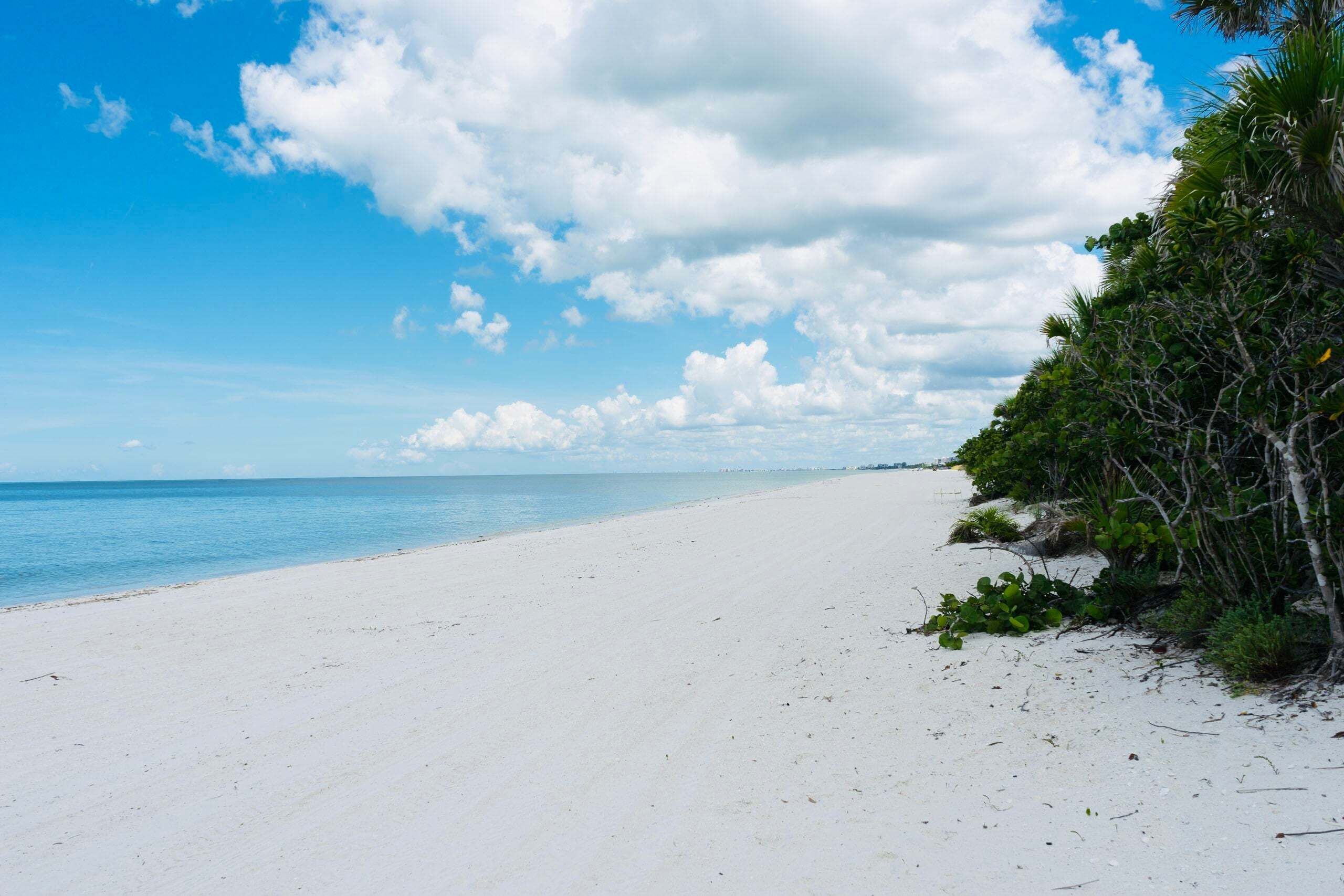 A beach with white sand and clear blue water.
