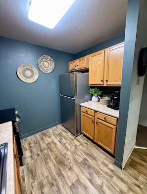 Une cuisine avec des meubles de rangement en bois, un réfrigérateur en acier inoxydable et deux assiettes décoratives accrochées au mur.