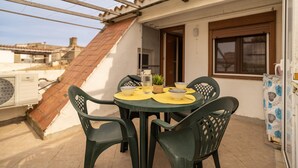 A rooftop terrace with a table set for four, surrounded by chairs, and a small potted plant. - Ref. CANYET : Charming House in the Heart of l’Escala with Terrace and Air Conditioning (L'Escala)