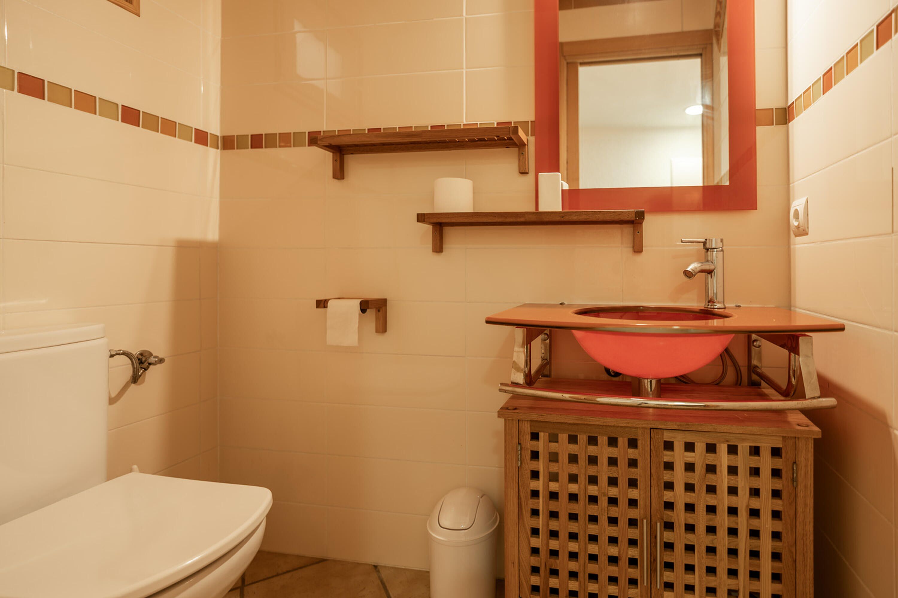 Ein Badezimmer mit Toilette, Waschbecken, Spiegel und Holzschrank.
