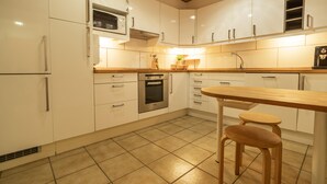 A kitchen with white cabinets, a wooden table, and two stools. - Ref. CANYET : Charming House in the Heart of l’Escala with Terrace and Air Conditioning (L'Escala)