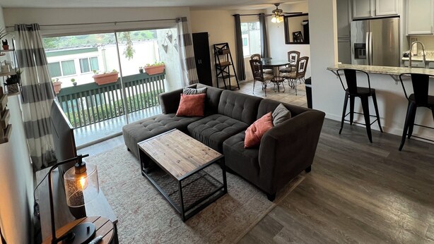 A modern living room with a sectional sofa, a coffee table, and a dining area with chairs. - Tranquil 2-bedroom condo in San Diego perfect for your getaway (San Diego)