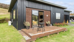 Un bâtiment moderne doté d’une terrasse en bois, de sièges extérieurs et de plantes en pot.
