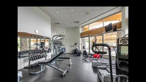 Une salle de sport équipée de tapis de course, d’haltères et d’appareils d’exercice.