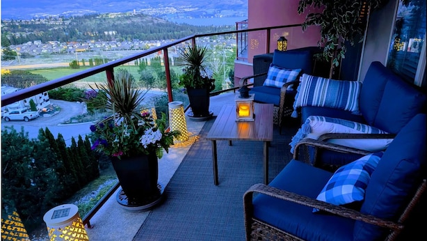 Un balcon agrémenté de meubles en osier, de plantes en pot et offrant une vue sur la ville.