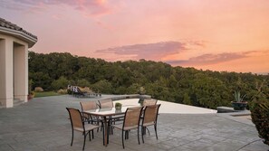 A patio with a table and chairs, surrounded by a lush forest. - Rancho Notso Grande by Avantstay Luxe Home, View (Templeton)