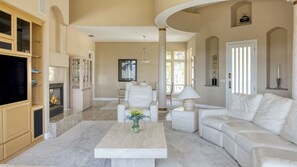 A spacious living room with a fireplace, white furniture, and a large window. - Rancho Notso Grande by Avantstay Luxe Home, View (Templeton)