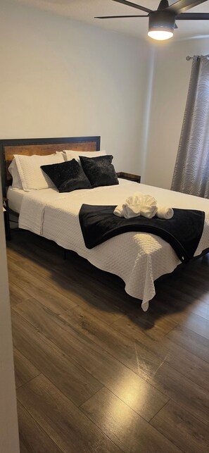 A single bed with a wooden headboard, white bedding, and a black throw blanket. - Spacious 4-bedroom house in awesome Davenport with AC (Davenport)
