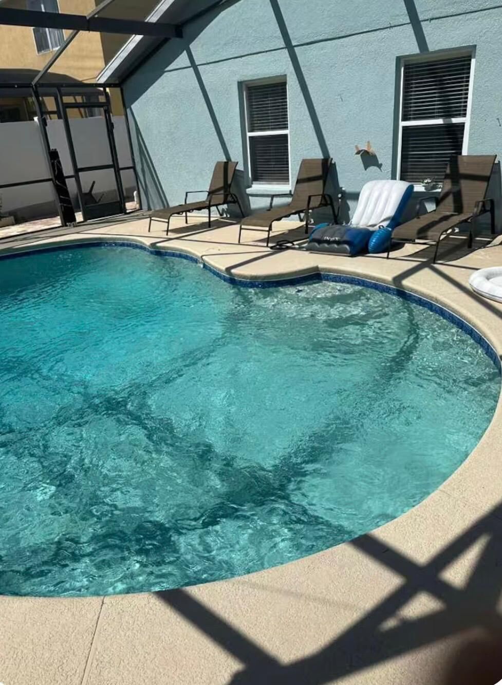 Uma piscina com espreguiçadeiras e área coberta.