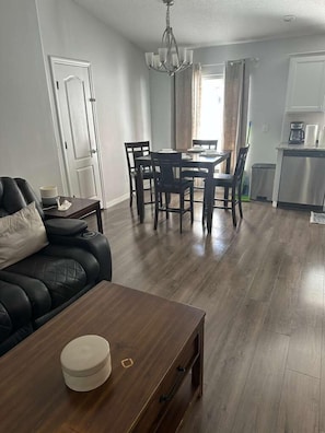 A living room with a black leather sofa, a wooden coffee table, and a dining area with a table and chairs. - Spacious 4-bedroom house in awesome Davenport with AC (Davenport)