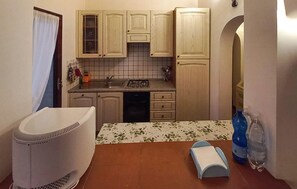 Une cuisine de taille réduite, dotée de meubles en bois, d’un plan de travail carrelé, d’un évier et d’une cuisinière.