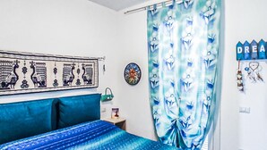 Un dormitorio con cama, un tapiz, una cortina y un adorno de pared.