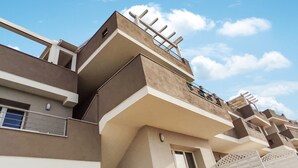 Un edificio residencial de varios pisos con balcones, techo plano y cielo despejado.
