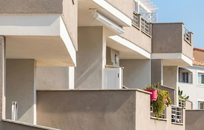 Ein mehrstöckiges Wohngebäude mit Balkonen, einer flachen Dachfläche und modernem Baustil.