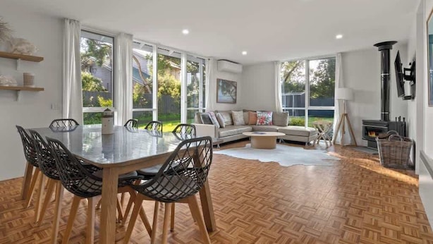 A modern living room with a dining area, large windows, a fireplace, and a view of the outdoors. - Sara by the sea, 400m to beach (Point Lonsdale)