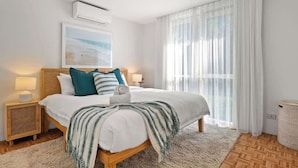 A bedroom with a bed, bedside tables, a lamp, a picture on the wall, and a window with curtains. - Sara by the sea, 400m to beach (Point Lonsdale)