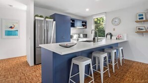 A modern kitchen with a central island, bar stools, and built-in appliances. - Sara by the sea, 400m to beach (Point Lonsdale)