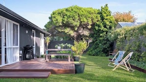 A backyard with a wooden deck, a barbecue grill, a bench, and two striped lawn chairs. - Sara by the sea, 400m to beach (Point Lonsdale)