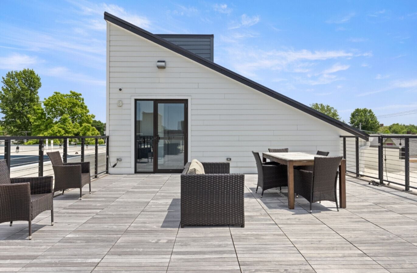 A rooftop patio with outdoor furniture, a glass door entrance, and a view of the street.