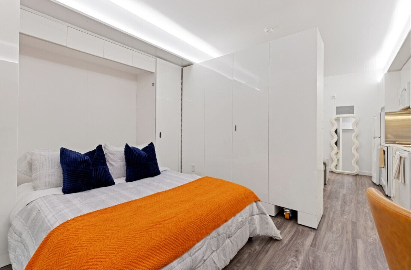 A bedroom with a bed, a wardrobe, and a bathroom visible in the background.
