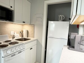 A compact kitchen with a stove, sink, and refrigerator.