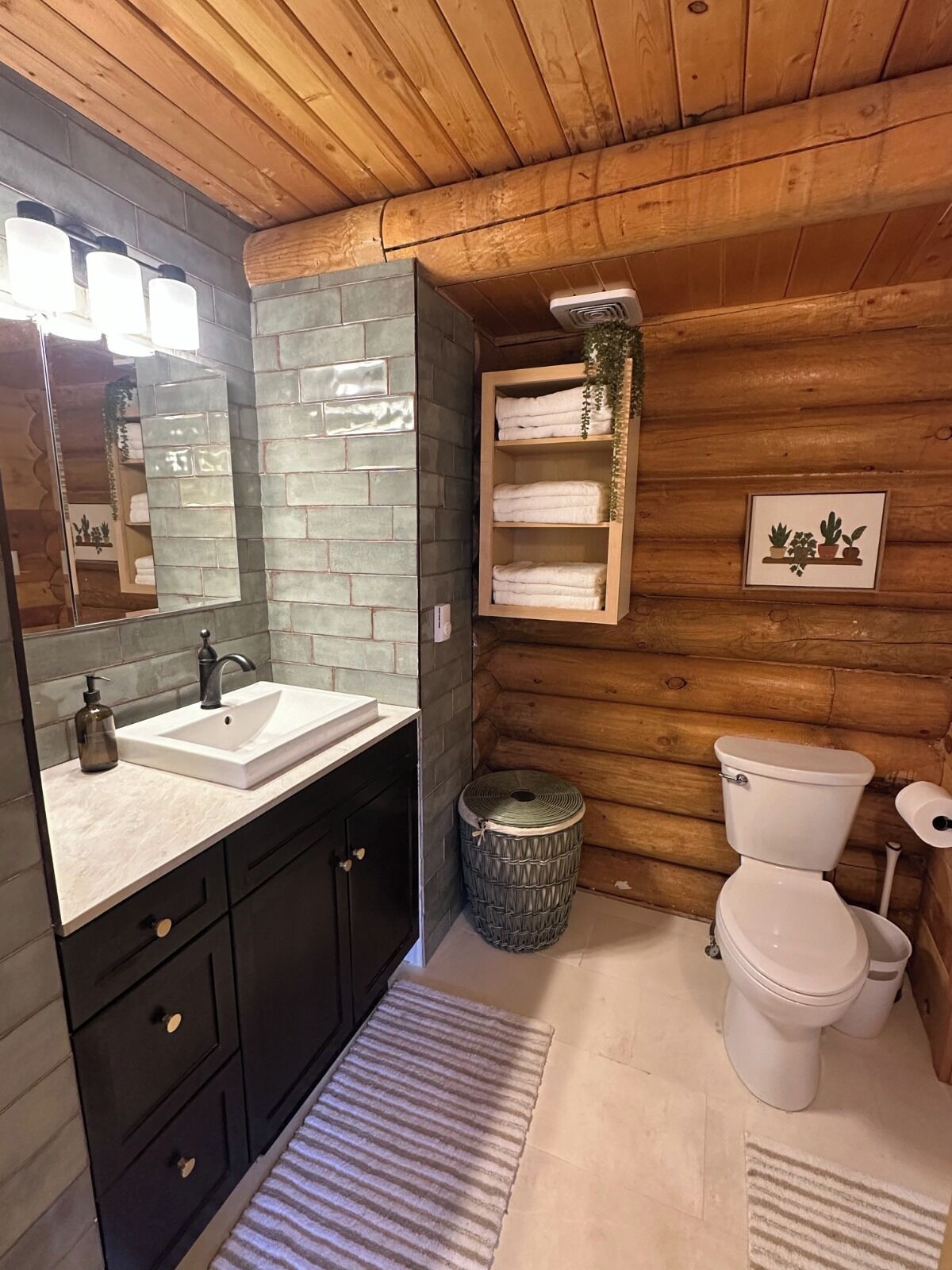 Une salle de bain avec un plafond en bois, un grand miroir, un lavabo, des toilettes et une étagère avec des serviettes.
