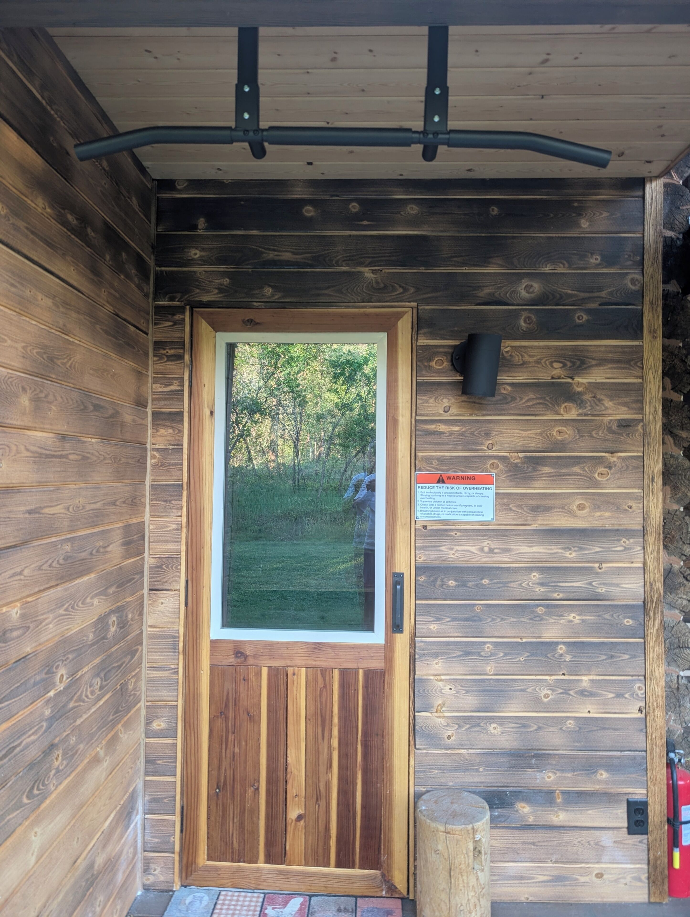 A wooden cabin with a door, a window, and a warning sign.