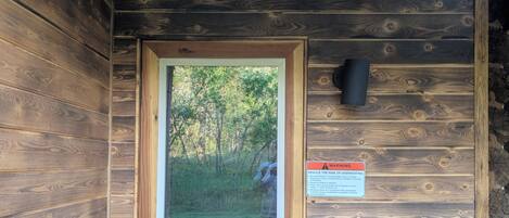 A wooden cabin with a door, a window, and a warning sign.