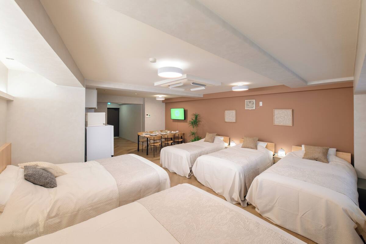 Una habitación de hotel con cuatro camas, una mesa de comedor y un televisor.