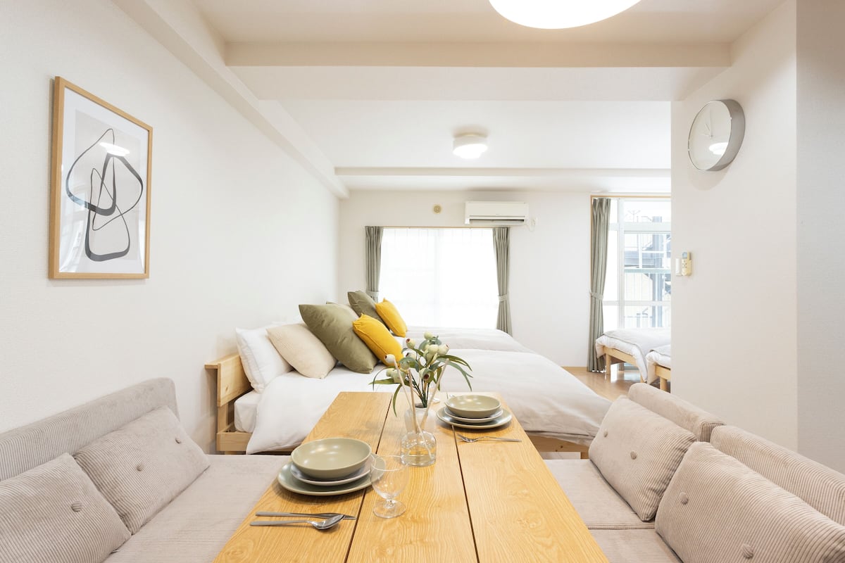 Una habitación de hotel con cama, una mesa de comedor de madera, un sofá y un cuadro en la pared.