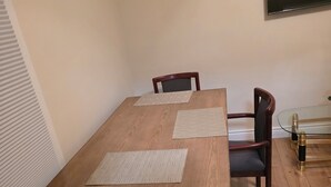Un tavolo da pranzo con quattro sedie, due sottopiatti e una lampada da tavolo in vetro.
