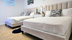 Un dormitorio con dos camas, una mesita de noche, una lámpara y un cuadro en la pared.
