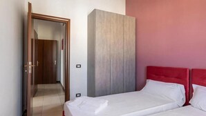 Una camera d'albergo con un letto, un armadio e una porta che dà su un'altra stanza.