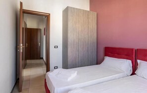 Ein Hotelzimmer mit einem Bett, einem Kleiderschrank und einer Tür zu einem anderen Raum.