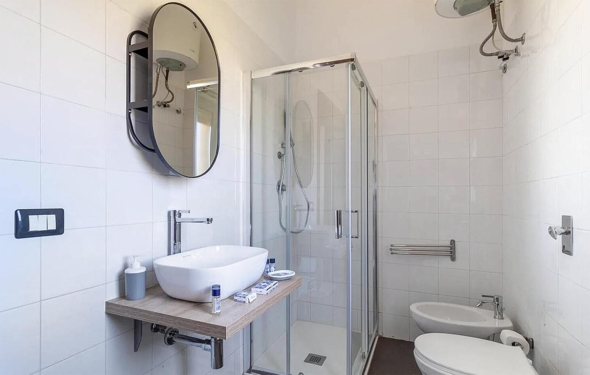 A modern bathroom with a glass-enclosed shower, a white sink, and a toilet.