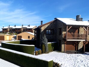 A snow-covered building with stone walls and wooden balconies, surrounded by snow. - Duplex ideal for families, swimming pool, fireplace and Wi-Fi (Sainte-Léocadie)