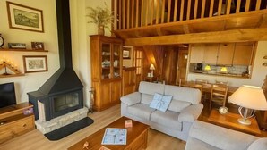 A cozy living room with a fireplace, a sofa, a coffee table, and a kitchen area. - Duplex ideal for families, swimming pool, fireplace and Wi-Fi (Sainte-Léocadie)