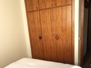 A wooden wardrobe with two doors, each with a heart-shaped keychain. - Duplex ideal for families, swimming pool, fireplace and Wi-Fi (Sainte-Léocadie)